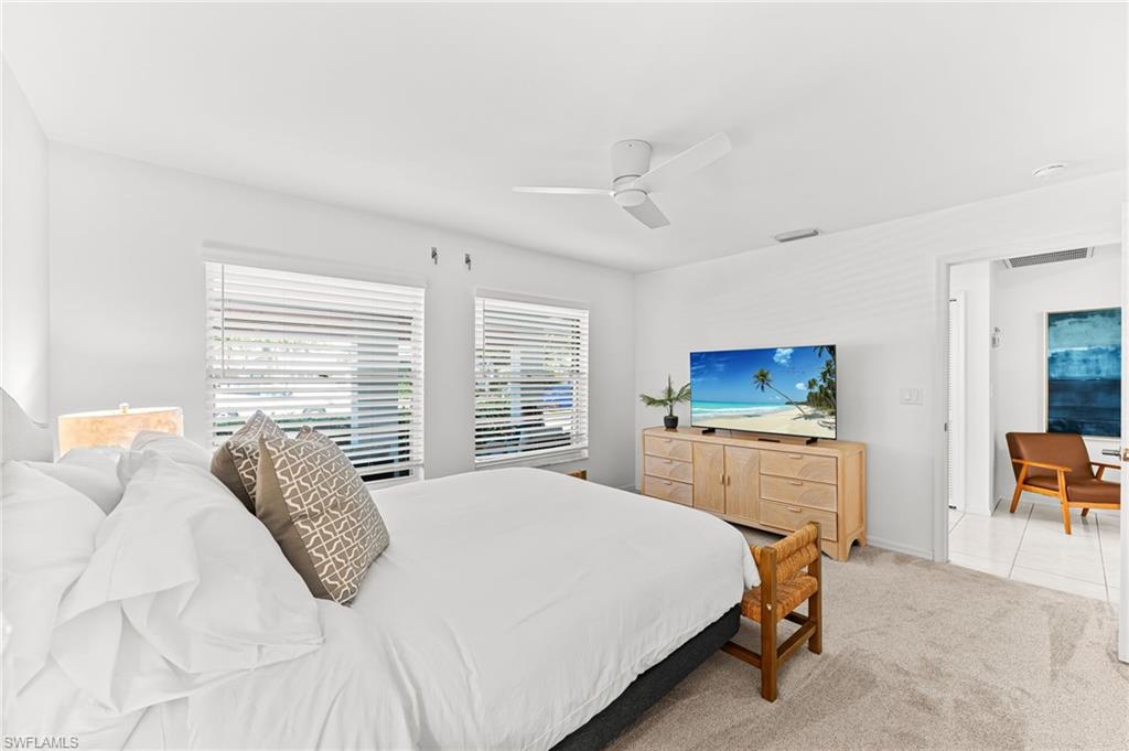 Bedroom with light colored carpet, ceiling fan, and light tile patterned flooring