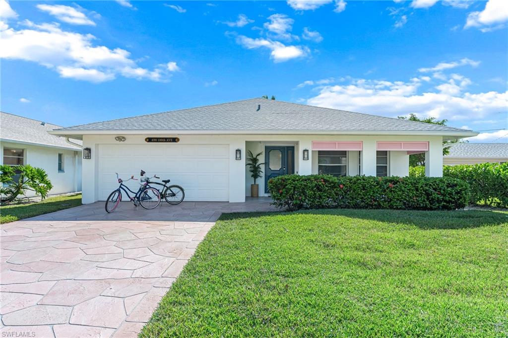 Ranch-style house featuring a front lawn, driveway, stucco siding, a shingled roof, and a garage
