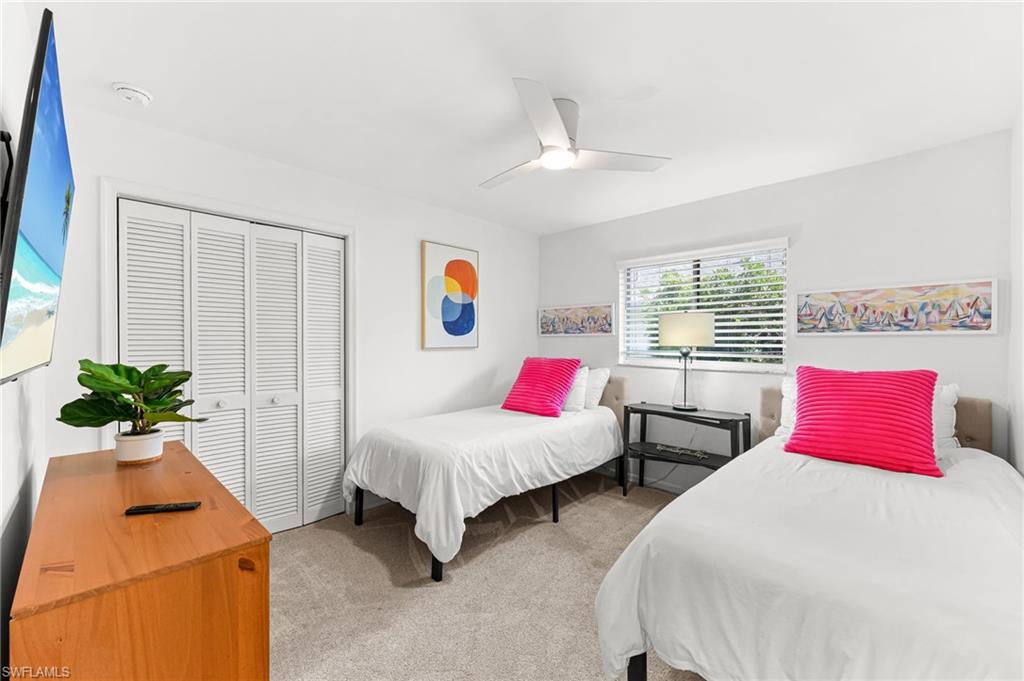 Bedroom with light carpet, a closet, and a ceiling fan