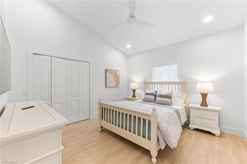 Bedroom featuring light wood-type flooring, lofted ceiling, recessed lighting, a ceiling fan, and a closet