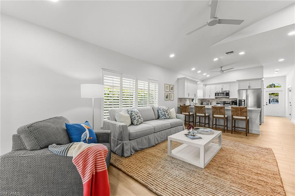 Living area featuring vaulted ceiling, recessed lighting, light wood finished floors, and ceiling fan