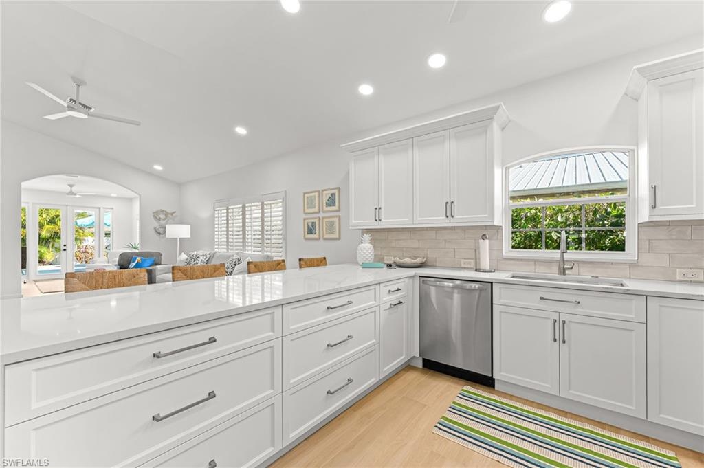 Kitchen with white cabinetry, recessed lighting, light stone countertops, stainless steel dishwasher, and arched walkways