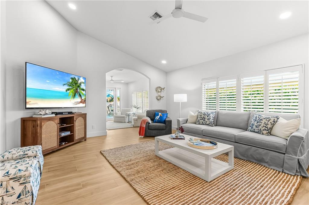 Living room with ceiling fan, arched walkways, light wood finished floors, and recessed lighting