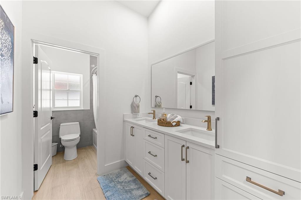 Bathroom featuring double vanity, light wood finished floors, and shower / bath combination with curtain