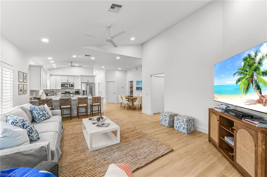 Living area with light wood-style floors, ceiling fan, recessed lighting, and high vaulted ceiling