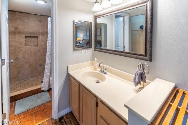 Recessed shower with tiled walls and floor, built-in shower niche, single vanity with integrated sink, and a large framed mirror