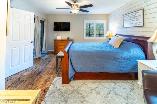 Hardwood-finish flooring, ceiling fan with integrated lighting, exterior access, and a window with plantation shutters