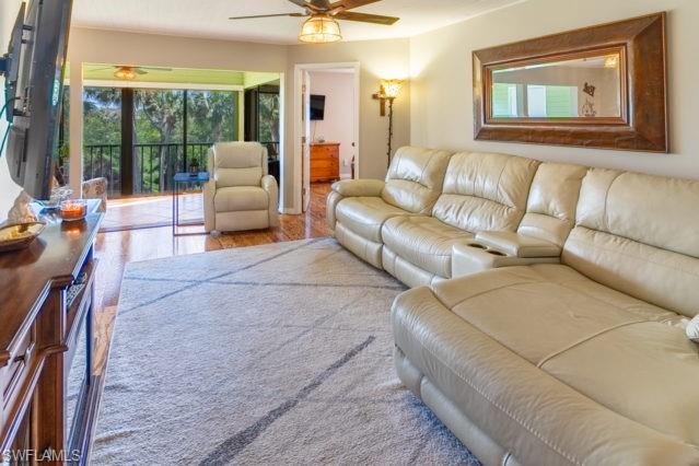 Wood-finish flooring throughout, ceiling fan with integrated lighting, and a screened outdoor living area