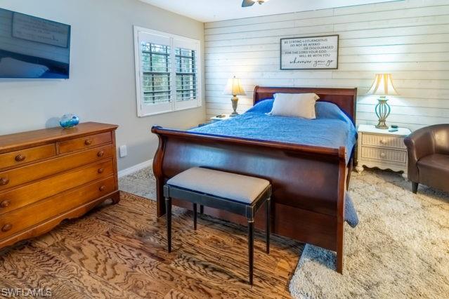 Wood-finish flooring, white shiplap accent wall, white window shutters, and ceiling fan
