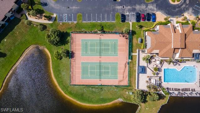 Multiple tennis courts, expansive swimming pool, substantial clubhouse, adjacent parking area, and surrounding green spaces
