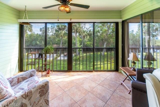 Screened enclosure featuring tiled flooring, a built-in ceiling fan, and multiple sliding glass doors