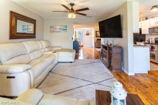 Wood-finish flooring, ceiling fan with integrated lighting, built-in entertainment console, and kitchen pass-through