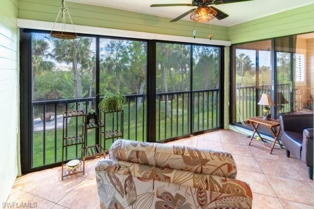 Enclosed porch with tiled flooring, horizontal plank walls, a ceiling fan, and screened sliding doors