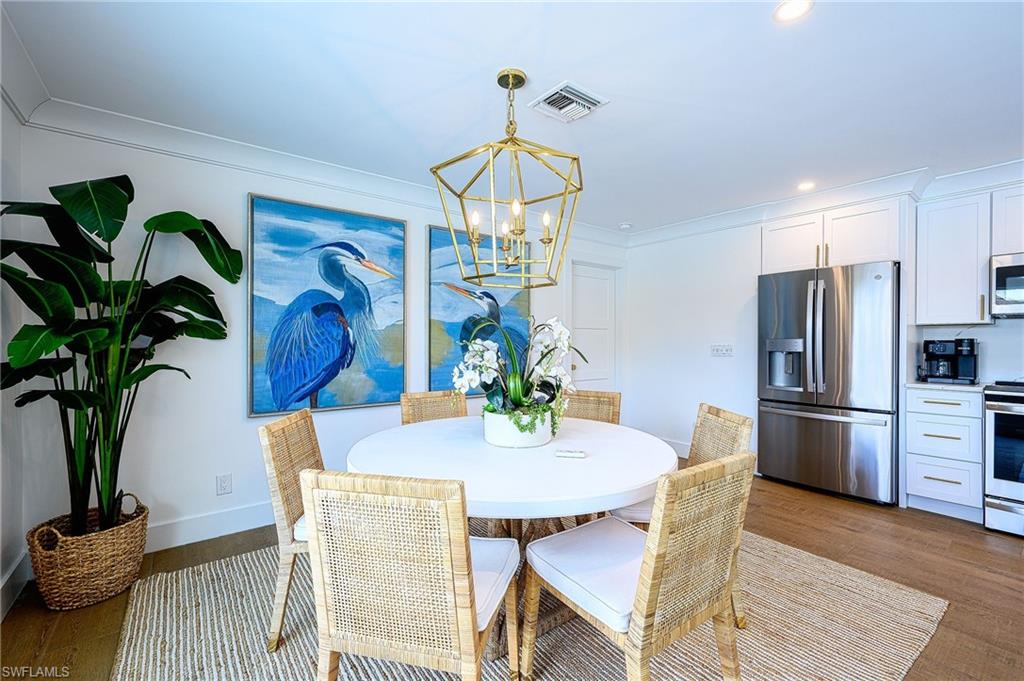 Dining area featuring an inviting chandelier, hardwood / wood-style flooring, and crown molding