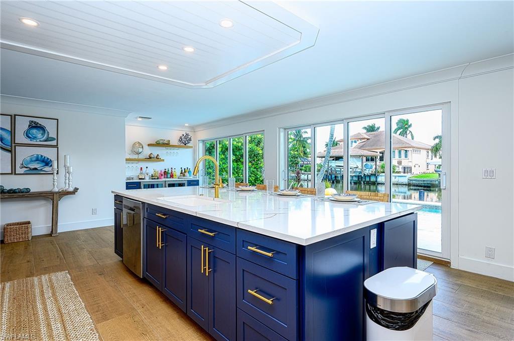 Kitchen with blue cabinetry, a kitchen island with sink, sink, and light hardwood / wood-style flooring