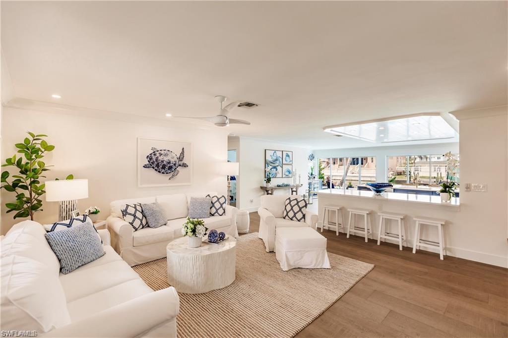 Living room with ceiling fan, hardwood / wood-style flooring, and crown molding