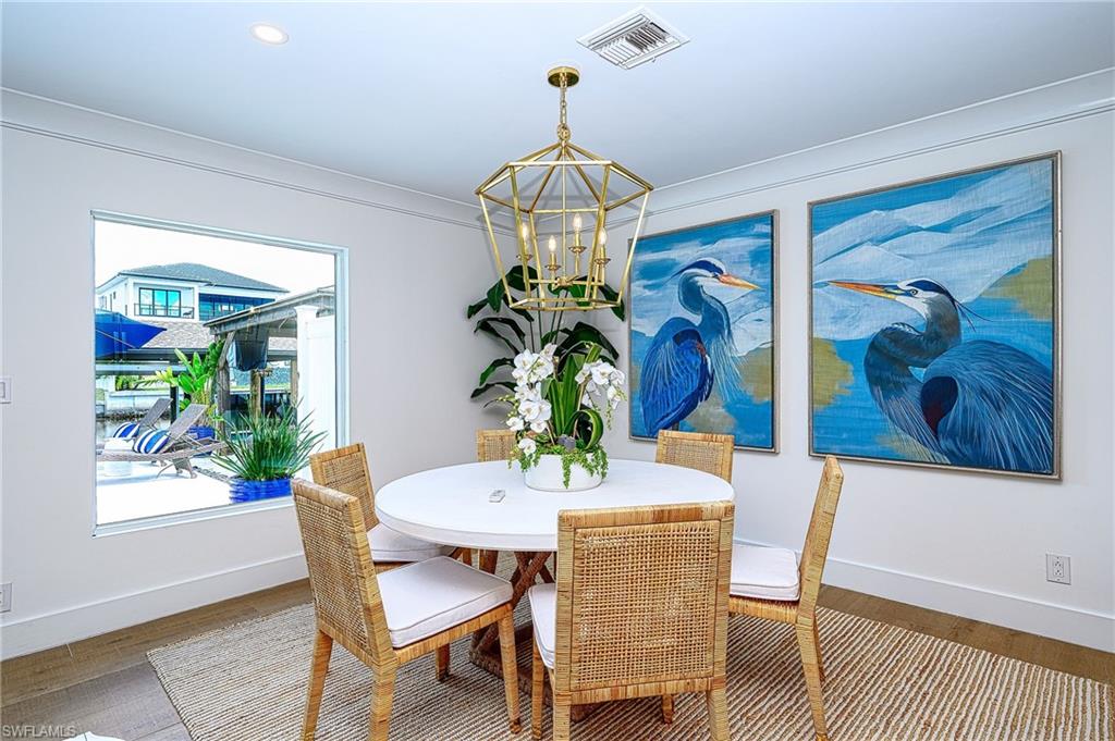Dining space featuring hardwood / wood-style flooring, crown molding, and a notable chandelier