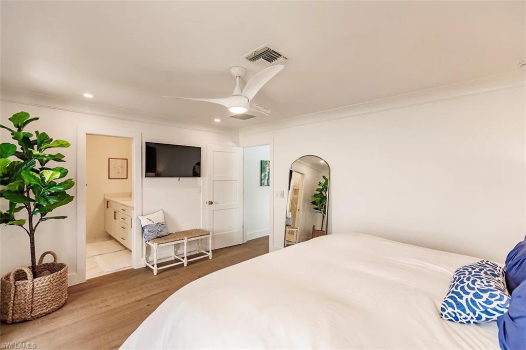 Bedroom featuring ceiling fan, light wood-type flooring, ensuite bath, and crown molding