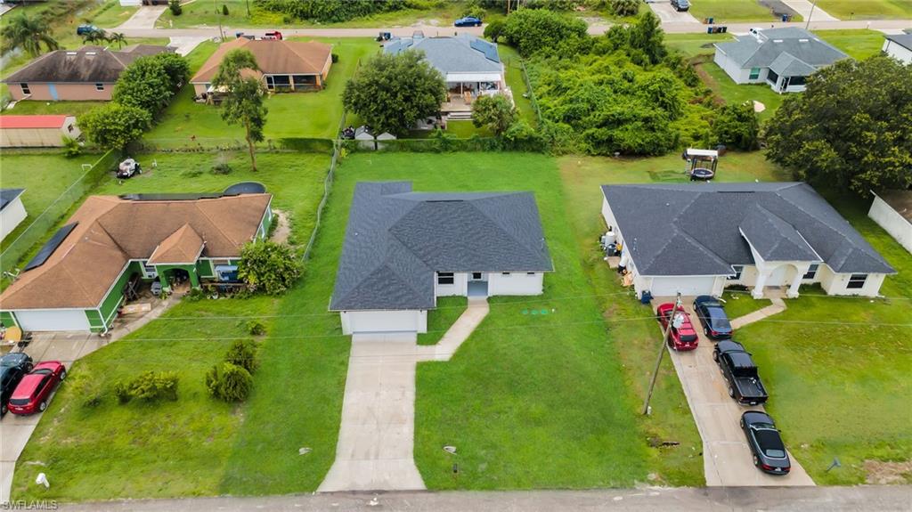 Single-story residence featuring a dark shingle roof and a concrete driveway(ENHANCED GRASS COLOR FOR VISIBILITY)