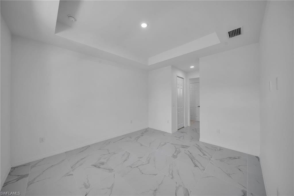 Recessed lighting, tray ceiling, tile flooring, and white walls
