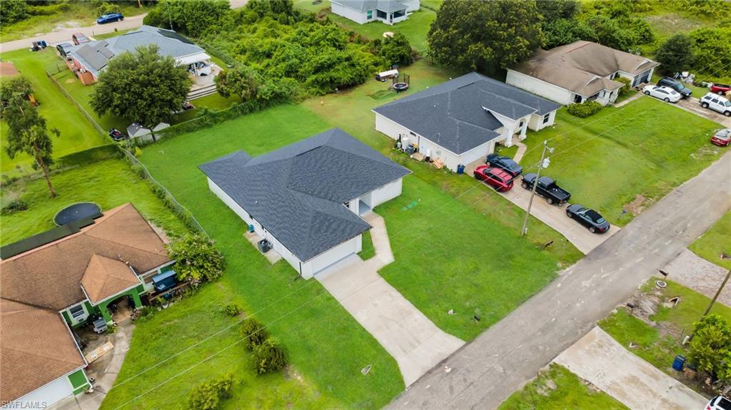 White exterior with a dark-pitched roof, an attached two-car garage, and a concrete driveway(ENHANCED GRASS COLOR FOR VISIBILITY )