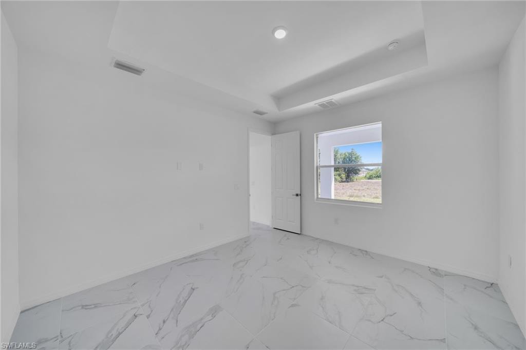 Recessed lighting illuminates the tray ceiling, complementing the white walls and large window