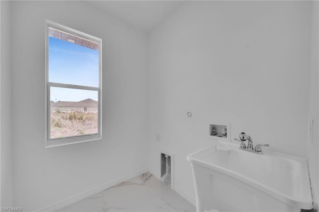 Utility sink with chrome faucet, large window, and white wall finishes