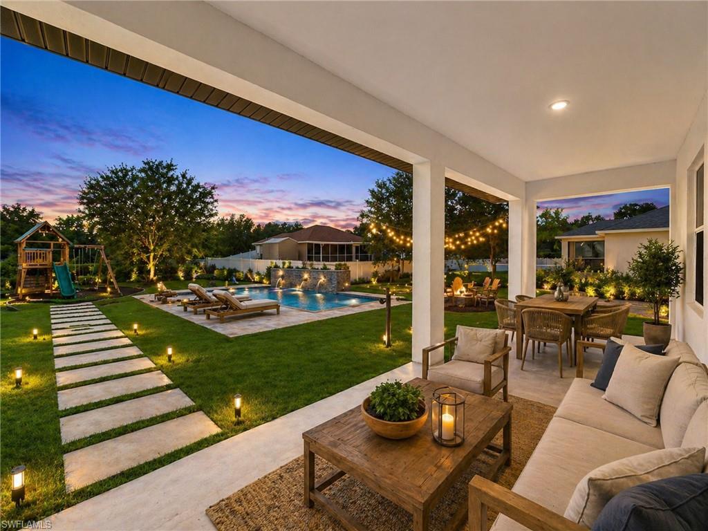 AI: IMAGINE THE POSSIBILITIES Resort-style backyard oasis featuring a resort-style pool with integrated spa, expansive manicured lawn, mature landscaping with accent lighting, composite paver pathway, covered loggia with ceiling fans and integrated seating area, and panoramic views of lush grounds at twilight