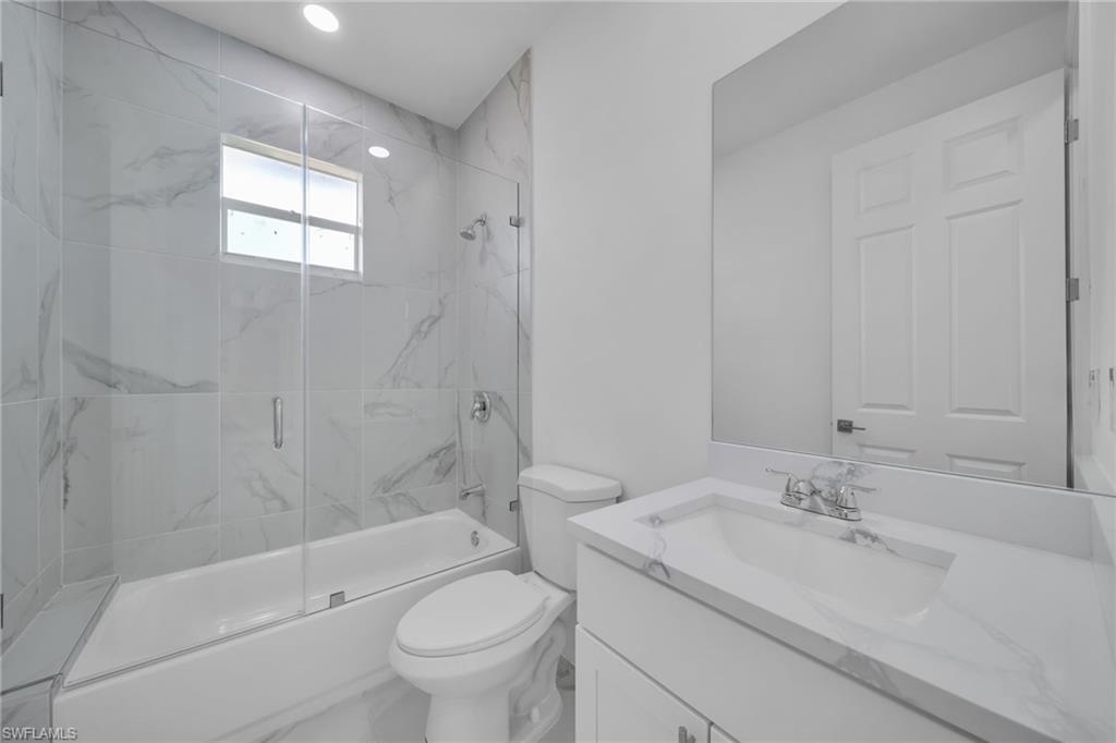 GUEST RESTROOM: Modern bathroom featuring a frameless glass-enclosed shower with marble-look tile surround and integrated rainfall showerhead, white subway tile flooring, dual vanity with white quartz countertop and rectangular vessel sink, polished chrome fixtures, and recessed ceiling lighting