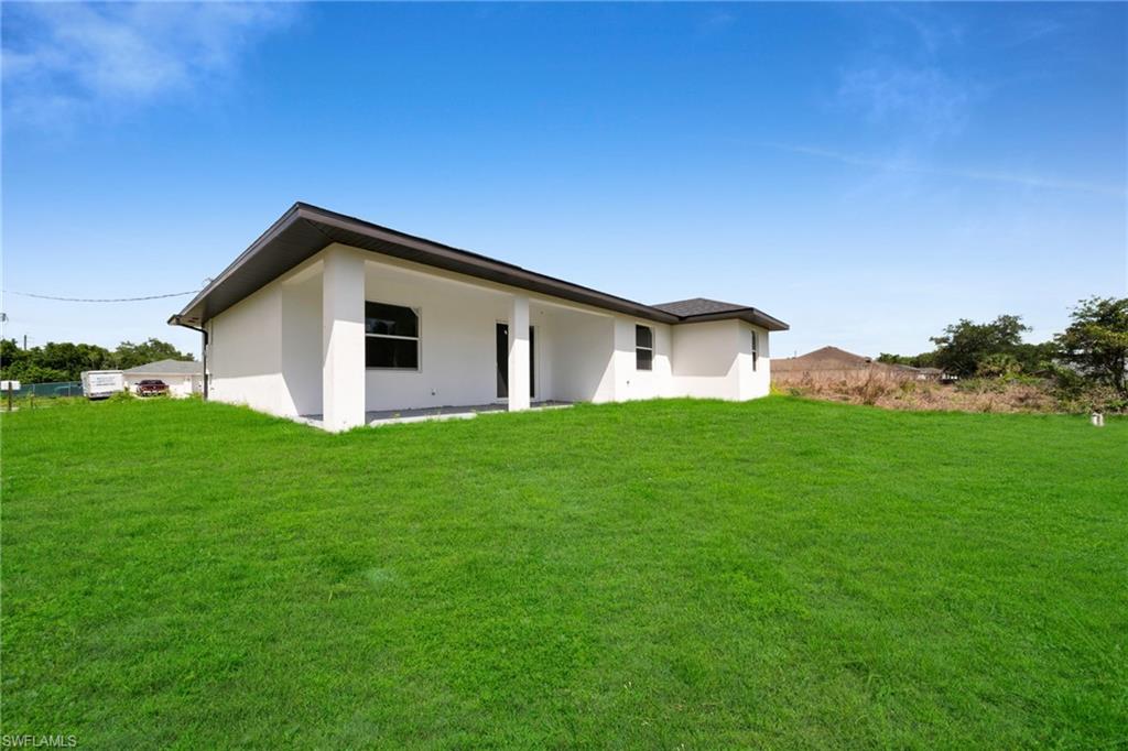 Expansive green lawn with a white stucco (ENHANCED GRASS COLOR)exterior and dark-pitched roof(ENHANCED GRASS COLOR)