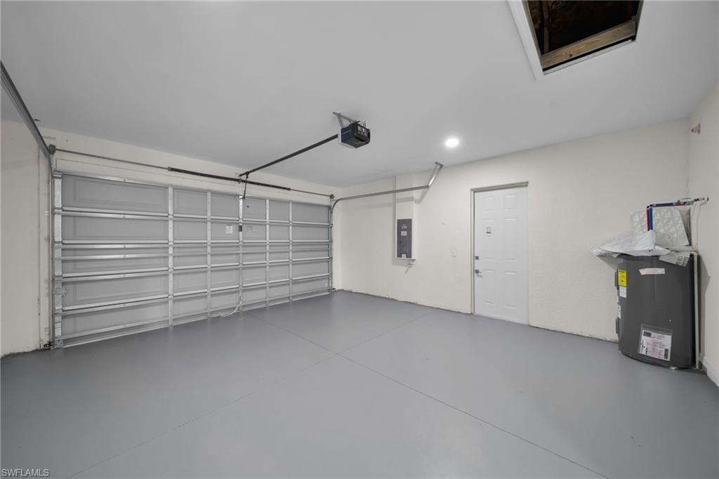 Spacious garage with a sectional overhead door, gray floor finish, built-in water heater, and a side access door