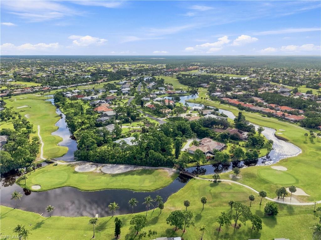 Aerial perspective featuring golf course frontage, multiple waterways, lush green landscaping, and residential properties