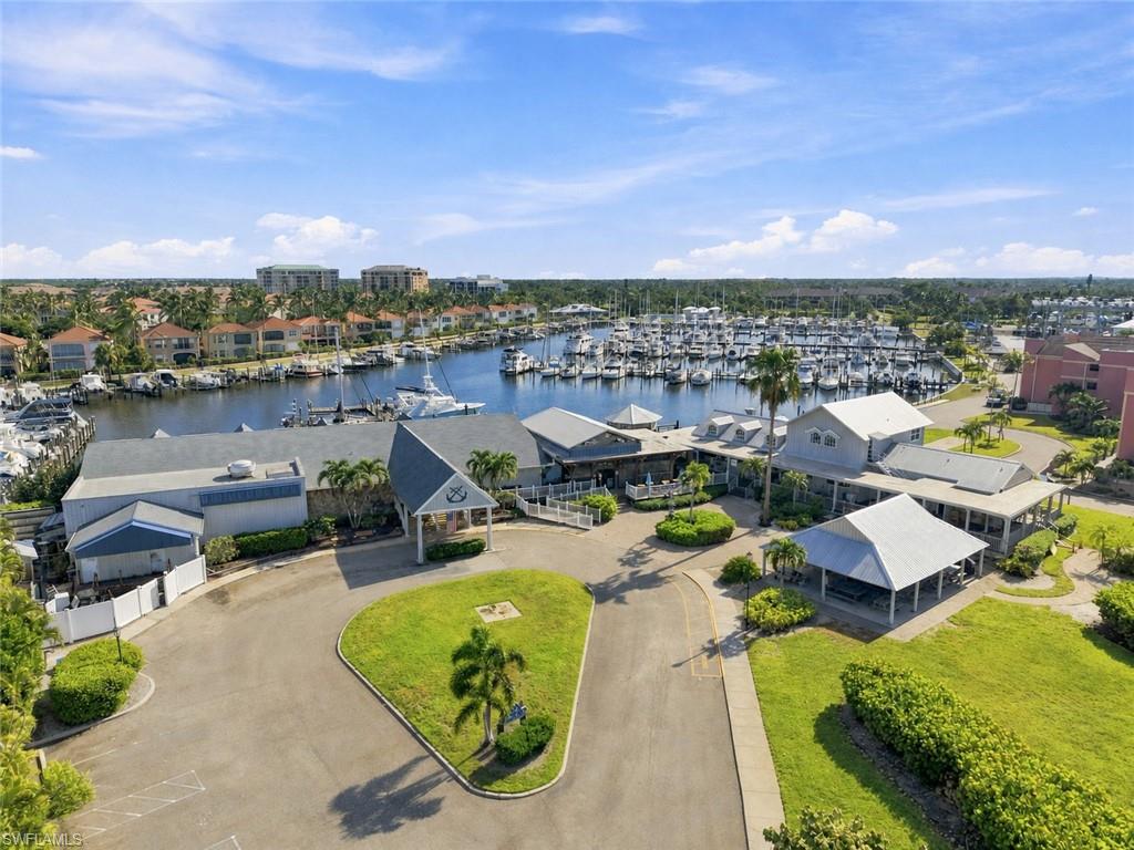 Marina-front property featuring multiple structures, paved parking areas, and abundant landscaping