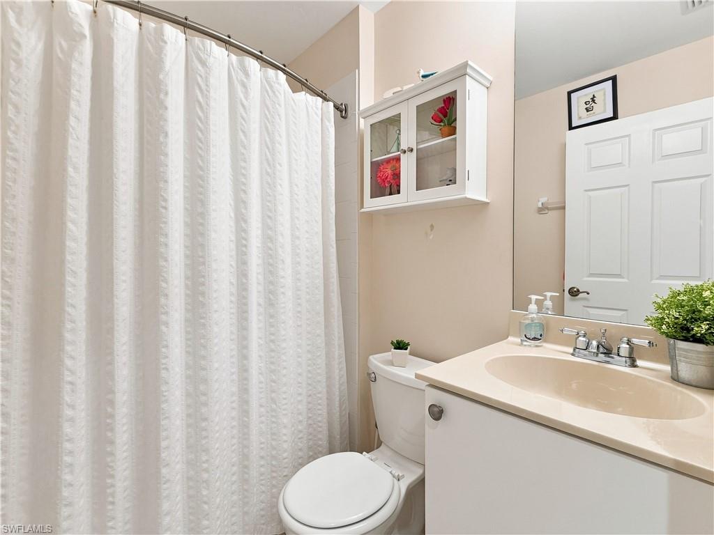 Bathroom featuring a curved shower rod, built-in cabinet with glass doors, single vanity with integrated sink, and a framed mirror