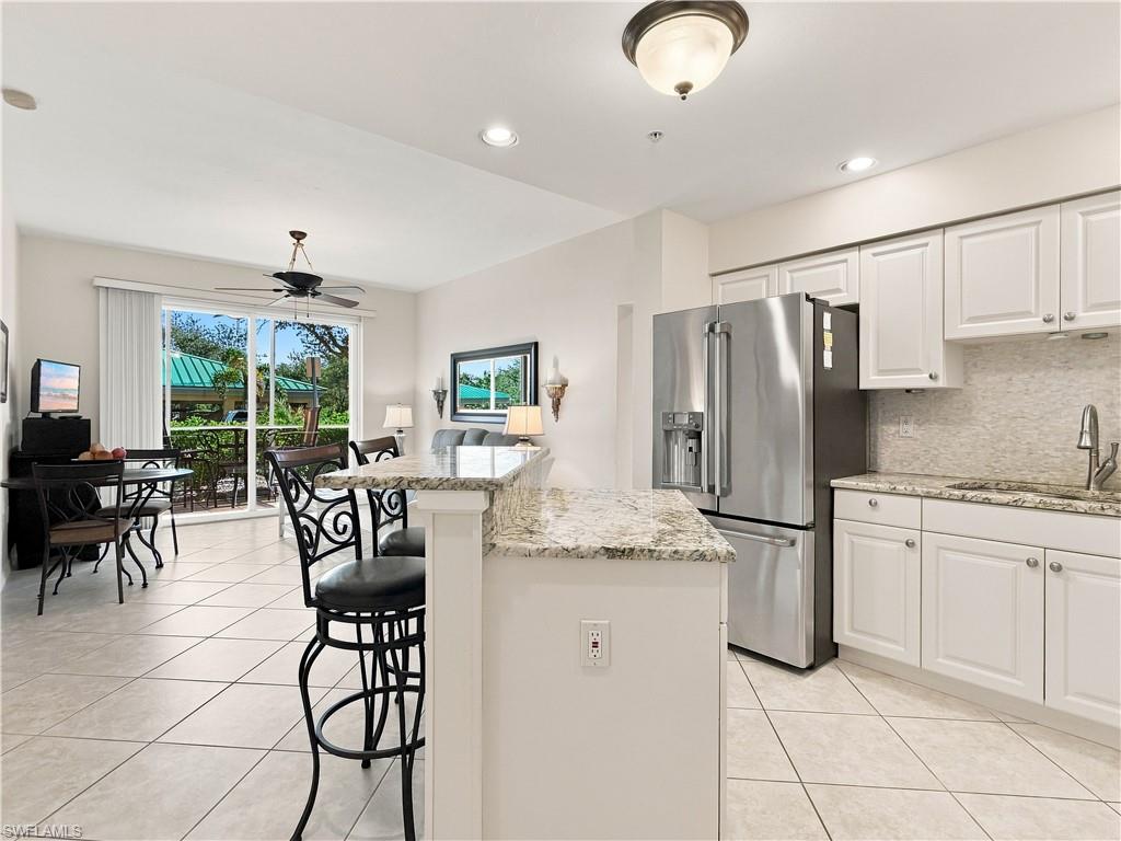 Kitchen featuring white cabinetry, stainless steel refrigerator, and granite countertops