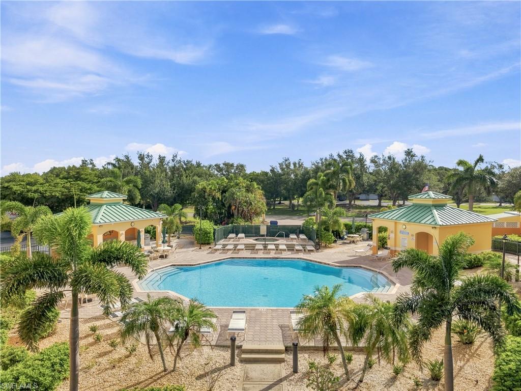 Expansive outdoor swimming pool with surrounding paver decking, two covered cabanas, and tropical landscaping