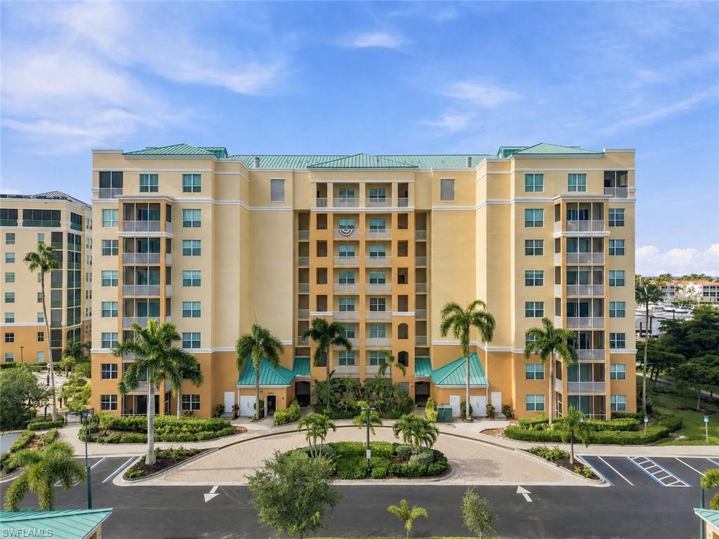 Multi-story residential building with a pastel yellow exterior, featuring multiple private balconies and screened lanais