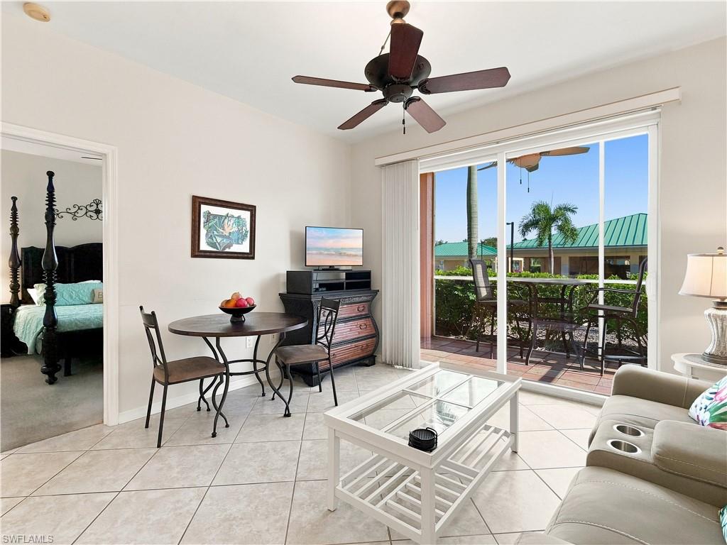 Sliding glass doors provide access to a private outdoor patio, featuring light-colored tile flooring and a ceiling fan