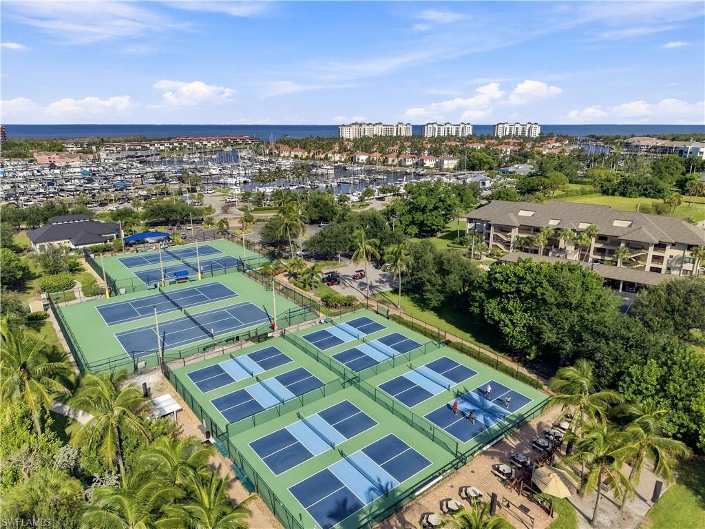 Tennis courts with fenced perimeters, adjacent pickleball courts, and a marina with multiple boats