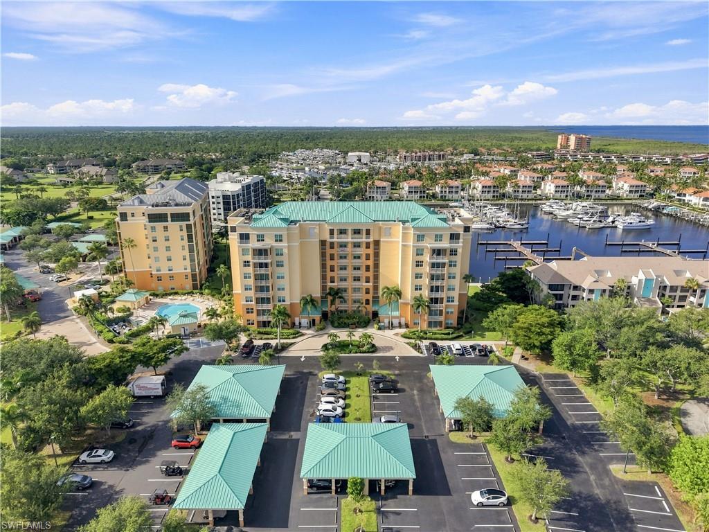 Multi-story residential complex with covered parking, an outdoor pool, and a marina with boat slips
