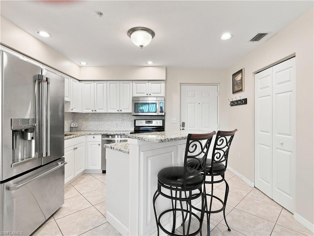 Kitchen featuring white cabinetry, stainless steel appliances, granite countertops, and tiled flooring