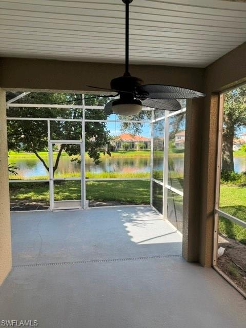 Screened patio featuring a ceiling fan with integrated lighting, a painted concrete floor, and a water backdrop