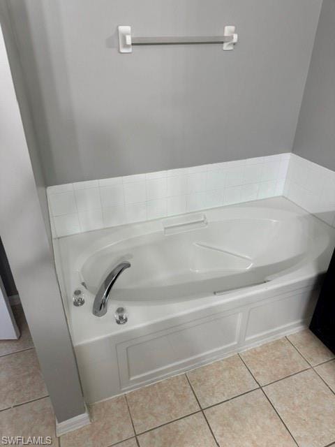 Built-in soaking tub with chrome fixtures, white tile surround, and neutral floor tile