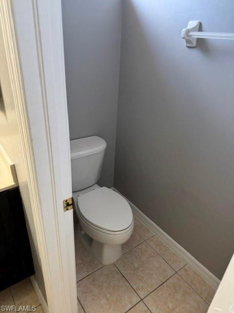 White toilet with neutral-toned tiled flooring and gray walls