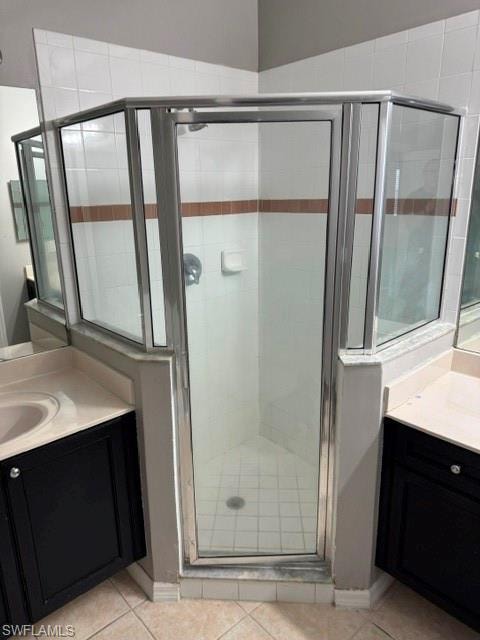 Glass-enclosed shower with white tiled walls and a decorative accent band