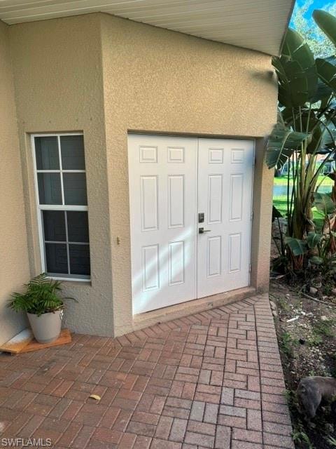 Stucco exterior with a covered entry, double panel doors, and a decorative window
