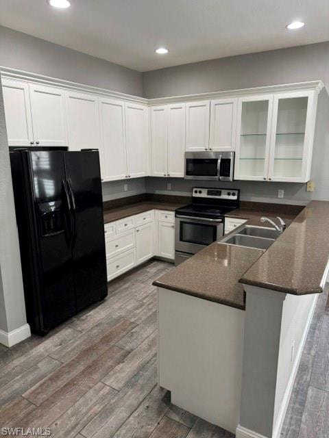 White cabinetry, stainless steel appliances, wood-finish flooring, recessed lighting, and a dual-basin sink