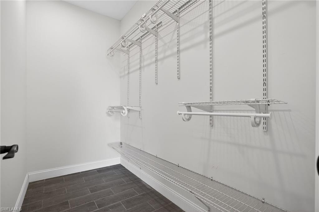 Adjustable wire shelving system with hanging rods and dark tile flooring