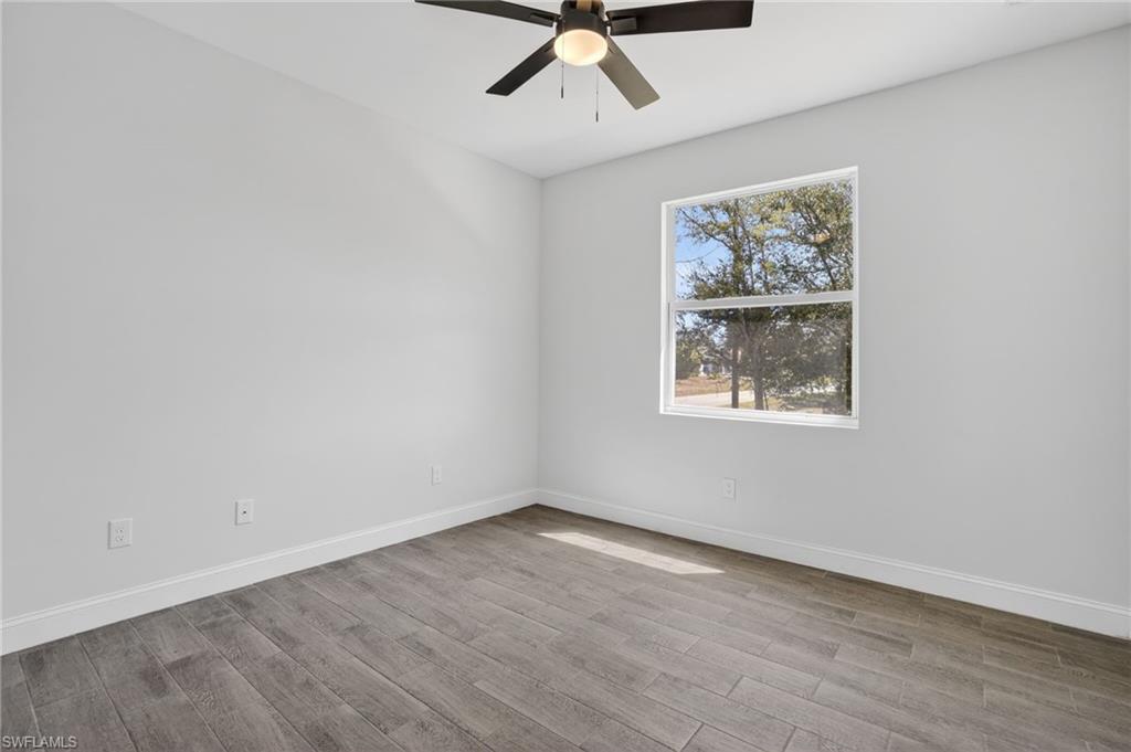 Room featuring wood-finish flooring, a ceiling fan with integrated lighting, and a single window