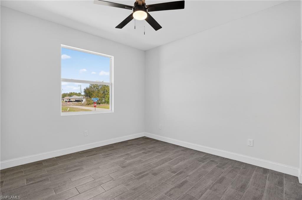 Recessed window, wood-finish flooring, ceiling fan with integrated lighting, clean white walls, and white trim